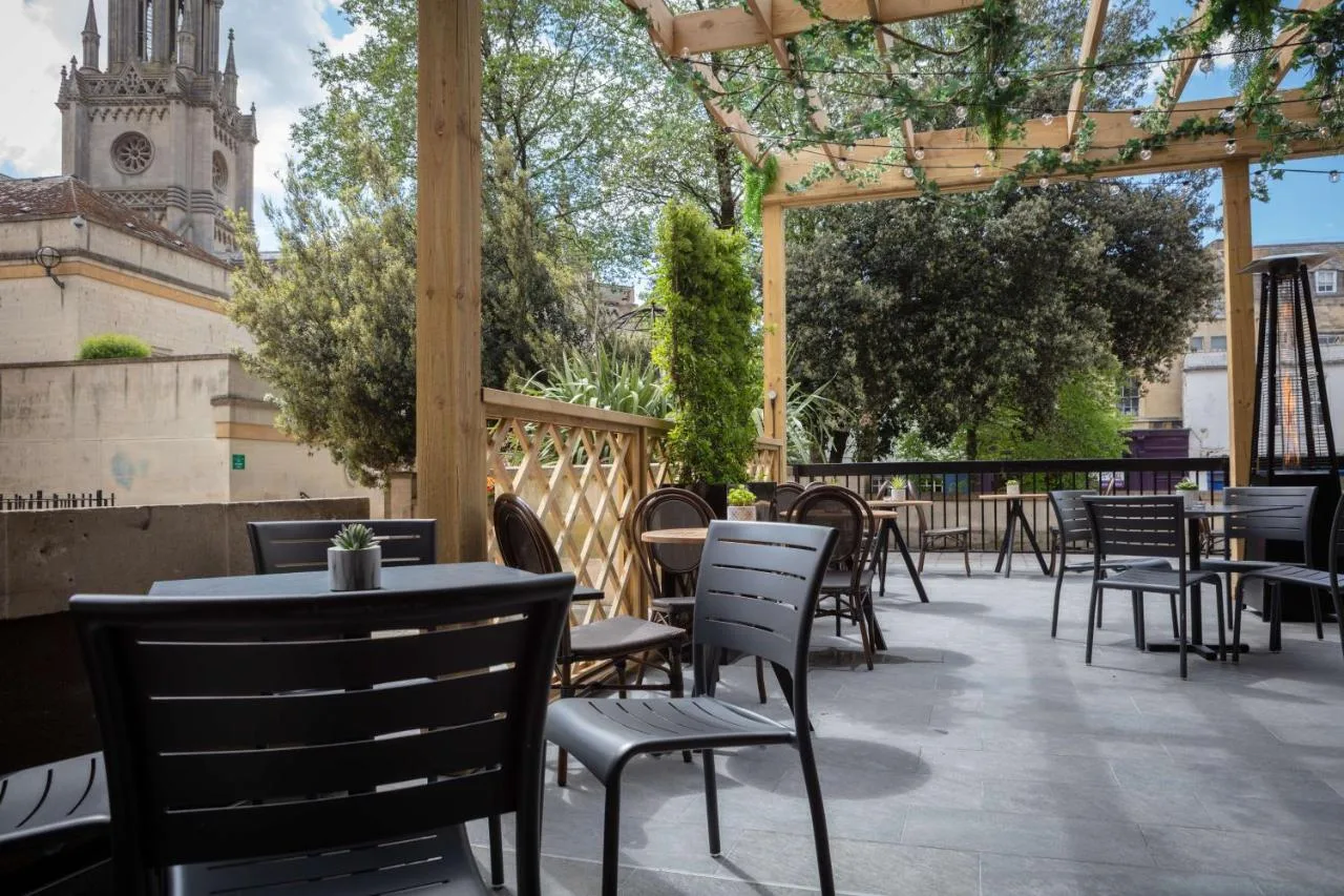 a patio with tables and chairs and a clock tower at DoubleTree by Hilton Bath in Bath