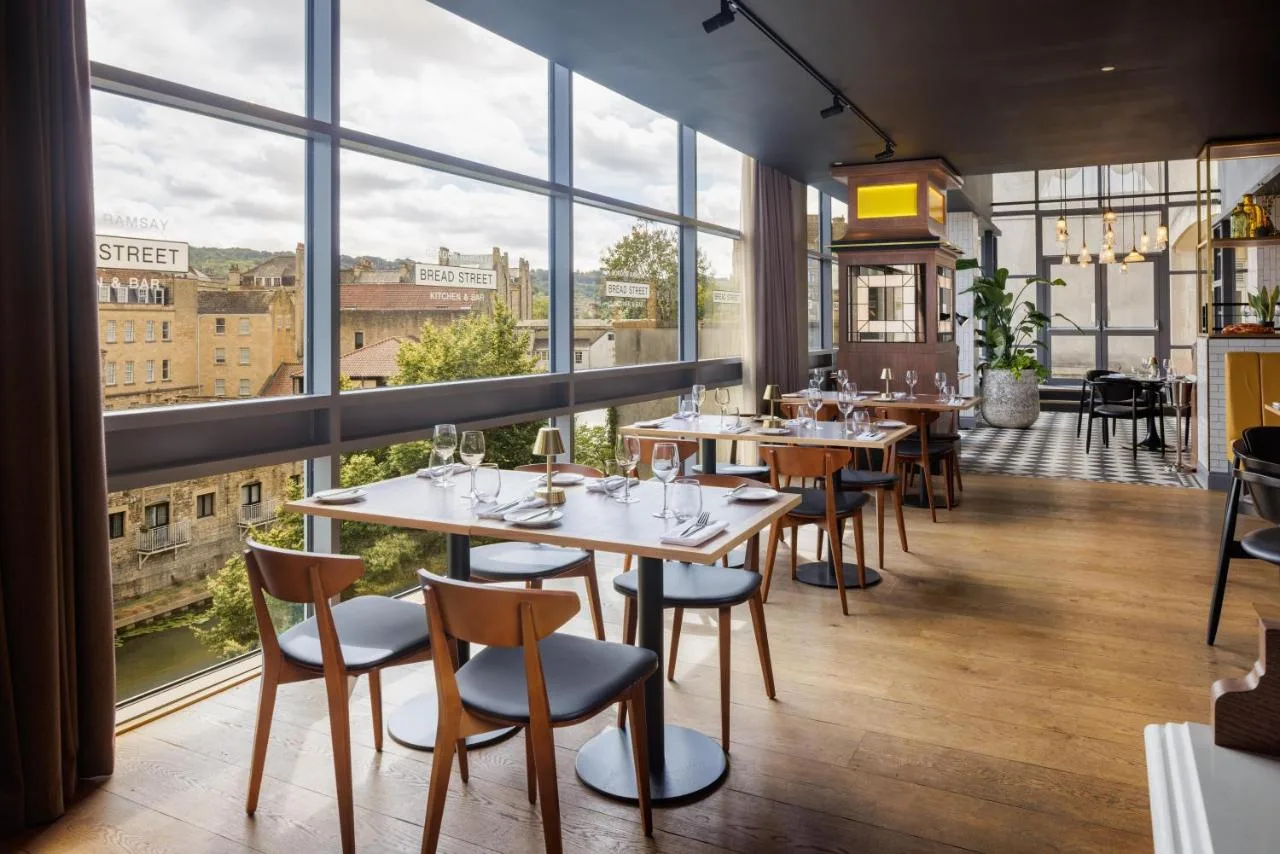 a restaurant with tables and chairs and large windows at DoubleTree by Hilton Bath in Bath