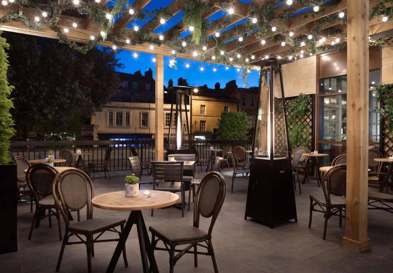 a patio with tables and chairs and lights at DoubleTree by Hilton Bath in Bath